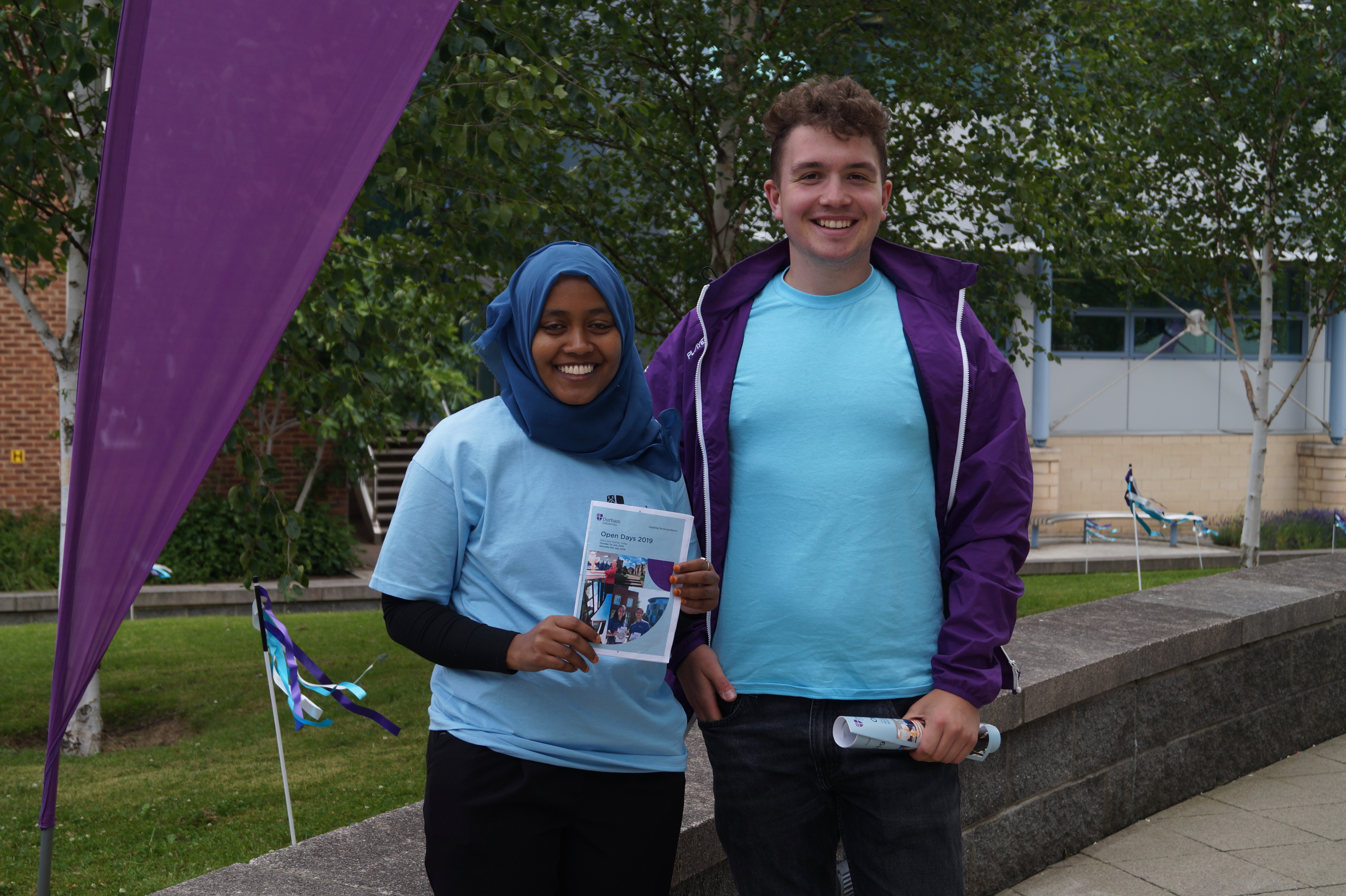 Two open day ambassadors, one holding an Open Day Guide
