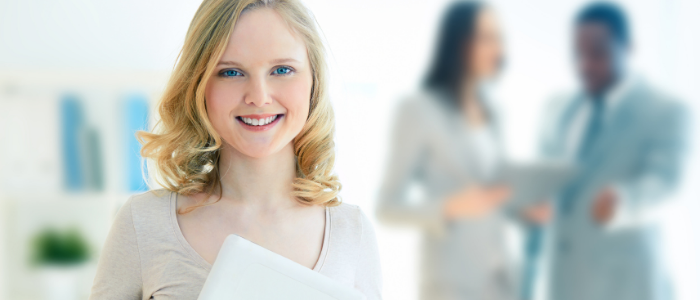 A young woman business intern standing smiling and holding papers