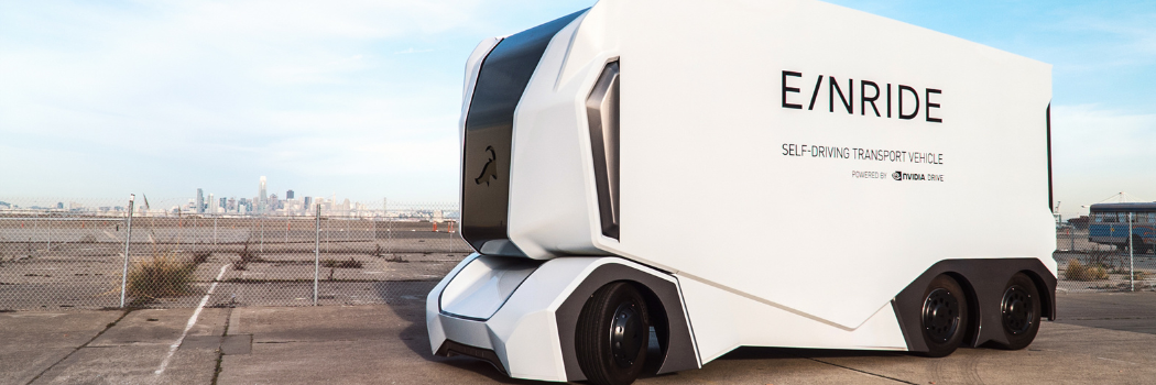 Einride self driving transport vehicle parked in carpark with cityscape behind