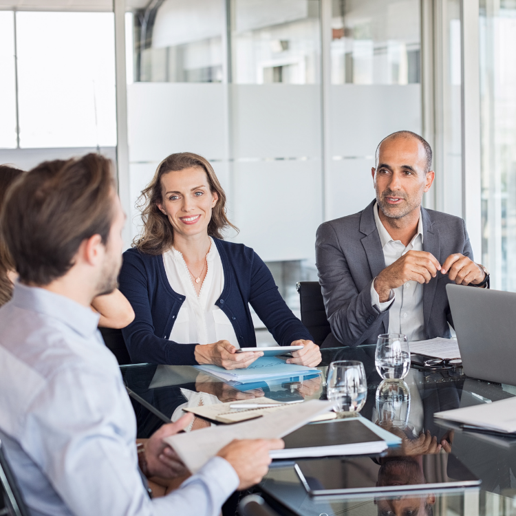 Three business people, a woman and two men, sit around a table