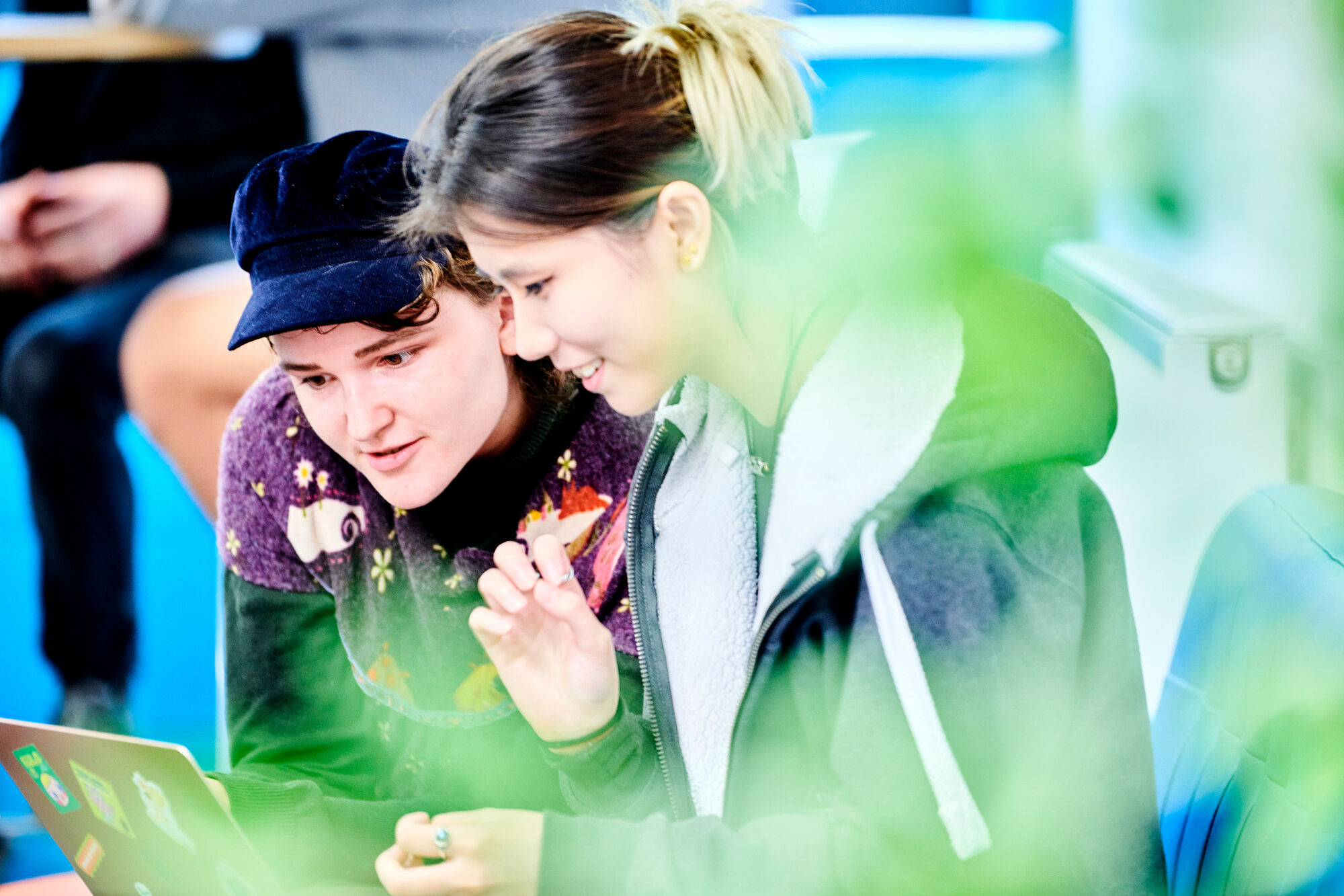 Young woman with a black hat talking to another young woman with dark hair