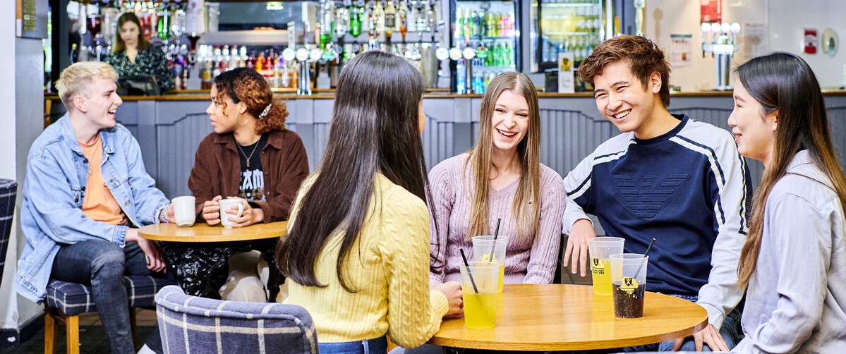 A diverse group of students laughing together in the college bar