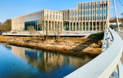 Image of a large modern building with water in the foreground