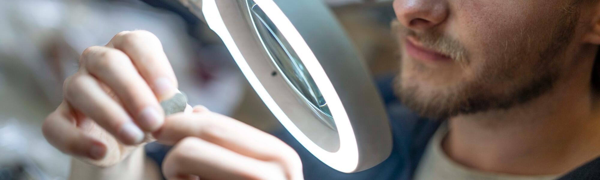 Person studying an artefact under a ring light