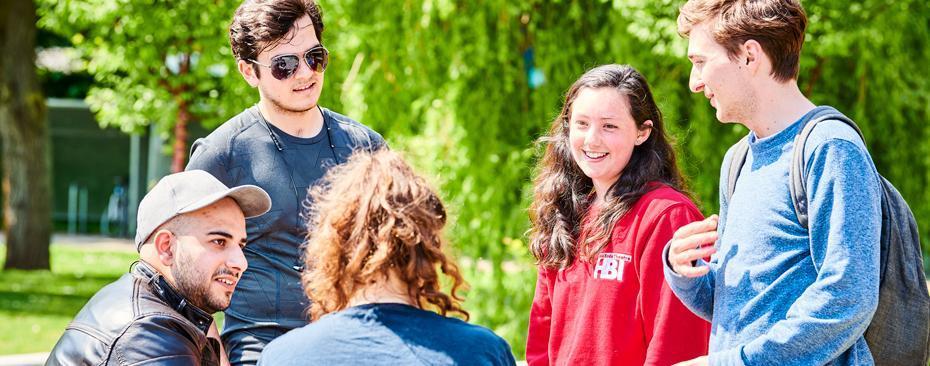 A small group of students chat on Lower Mountjoy Campus on a warm, sunny day