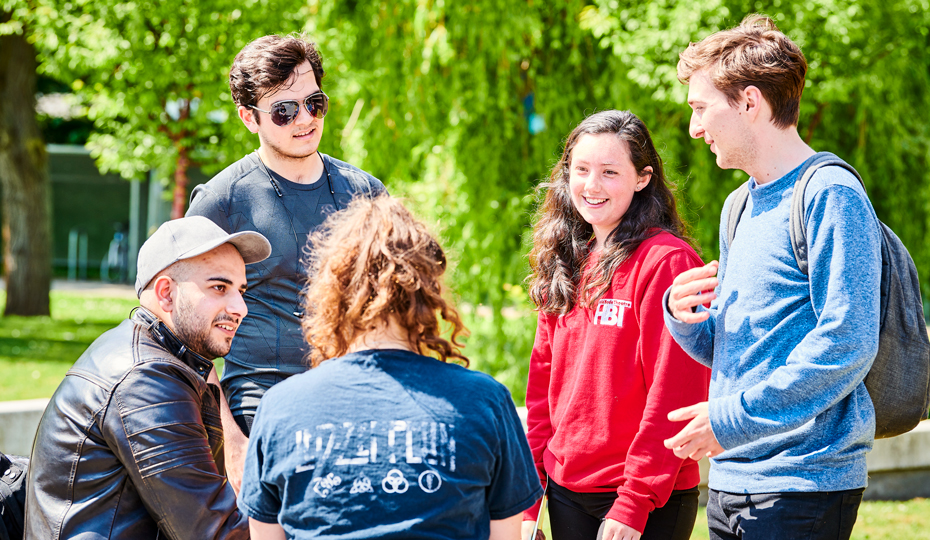 A small group of students chat on Lower Mountjoy Campus on a warm, sunny day
