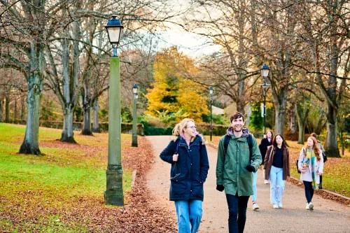 Two students walking on campus under autumnal trees