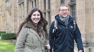 Two students walking past buildings on Palace Green