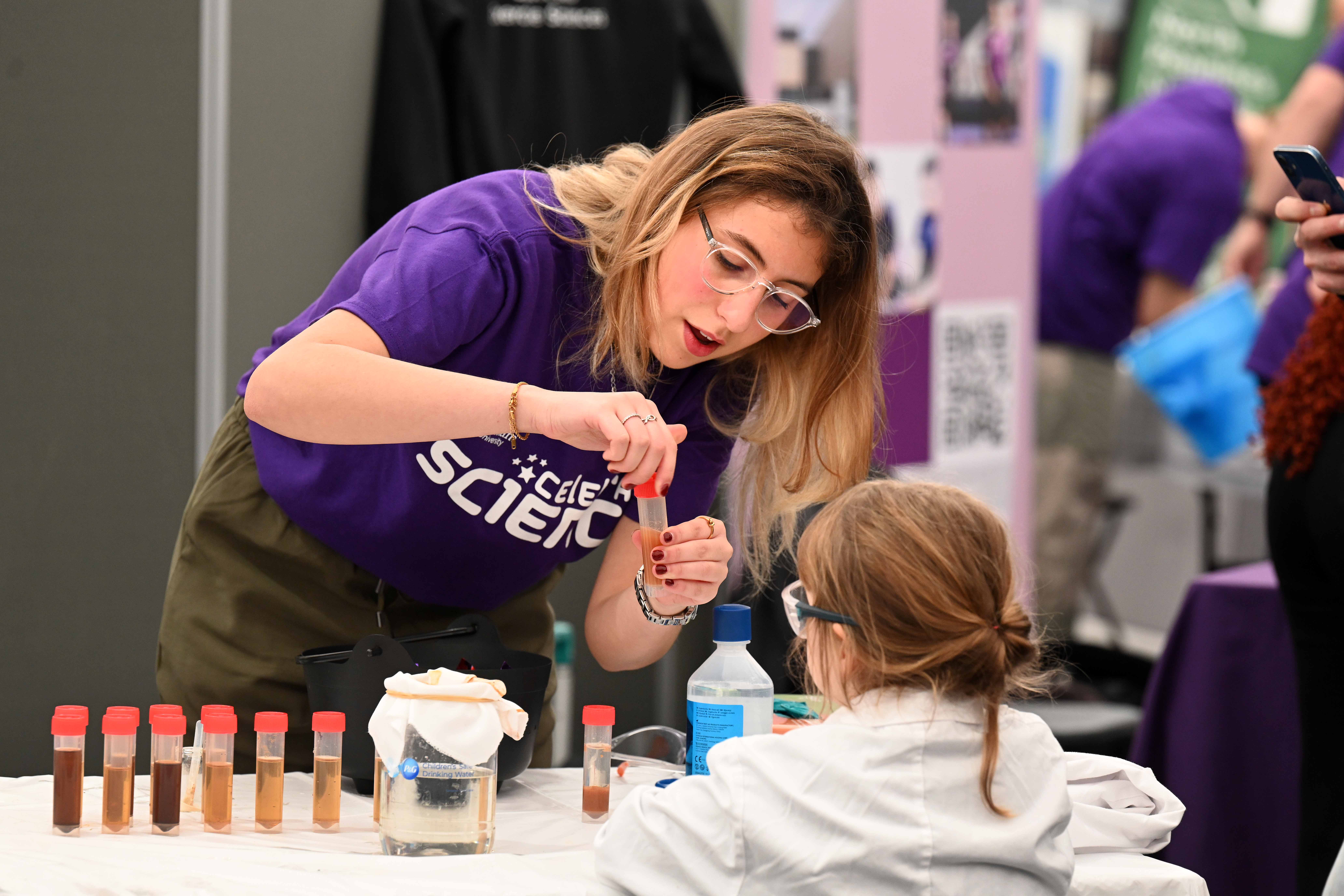 A Celebrate Science volunteer helps a child do and experiment with testtubes.
