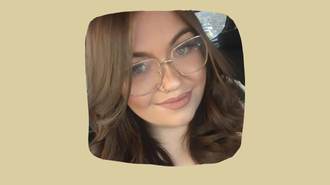 Student with dark hair and glasses smiling at the camara