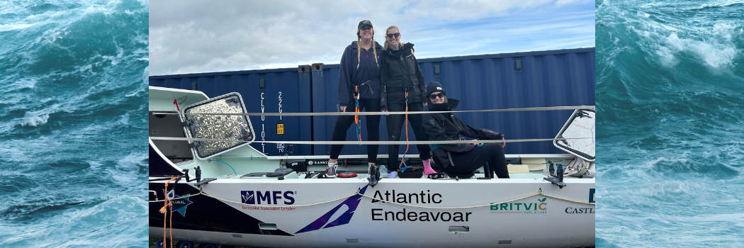 Grace Gilbert and crew member standing on rowing boat