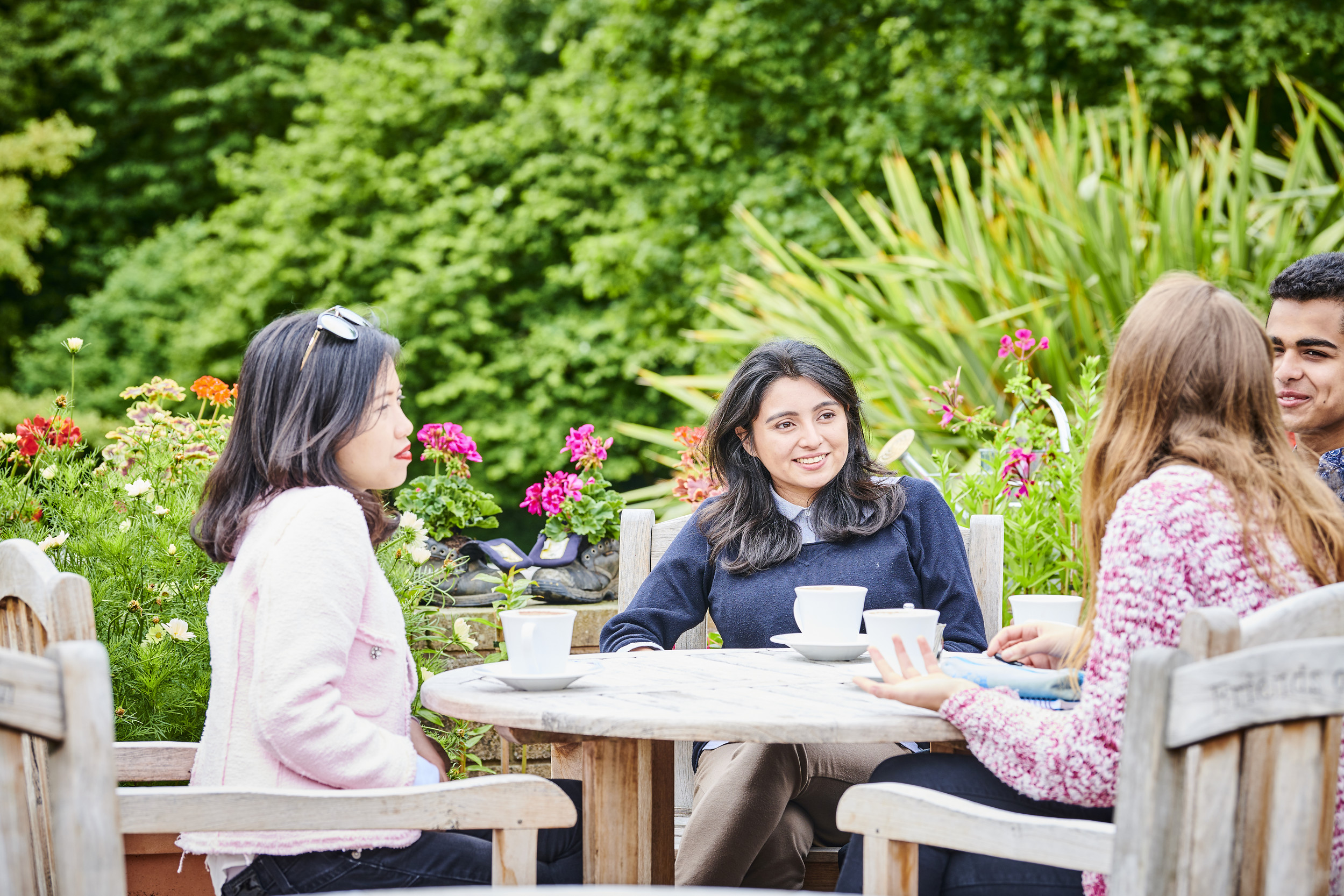 Students sat round a table with hot drinks in the Botanic Gardens