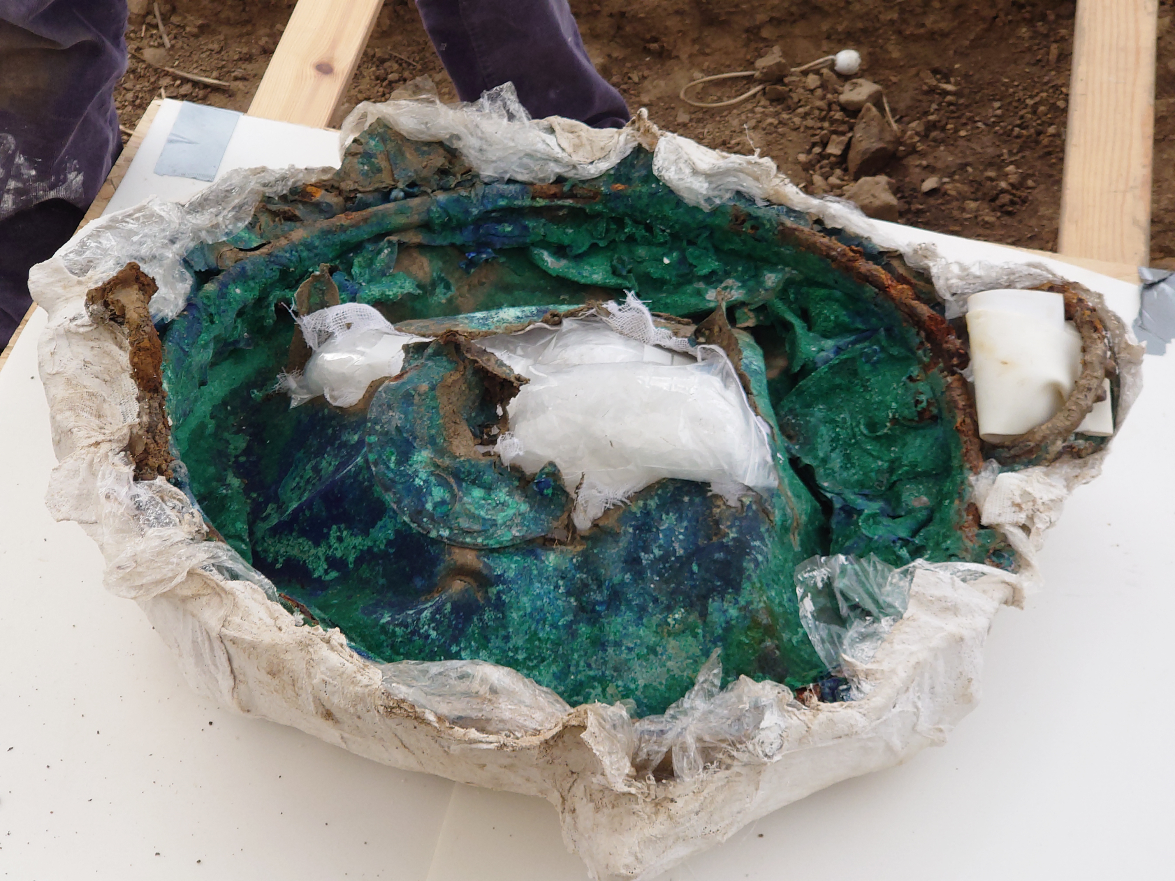 An Iron Age metal cauldron excavated from the Melsonby Hoard. The metal is blue and corroded in many places, with a large hole in the middle.
