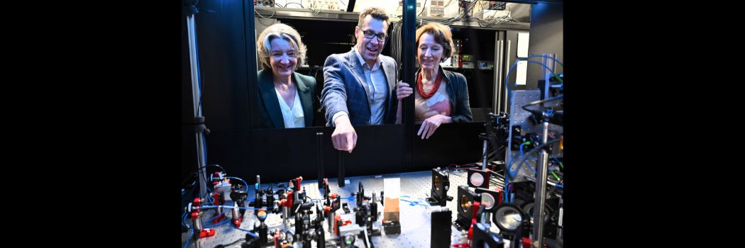 A man pointing to some scientific equipment, as he speaks with two women