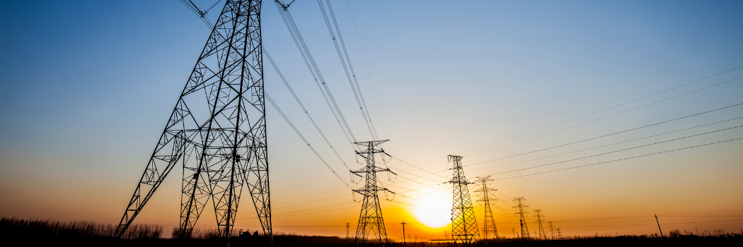 Electricity pylons with sun setting behind them