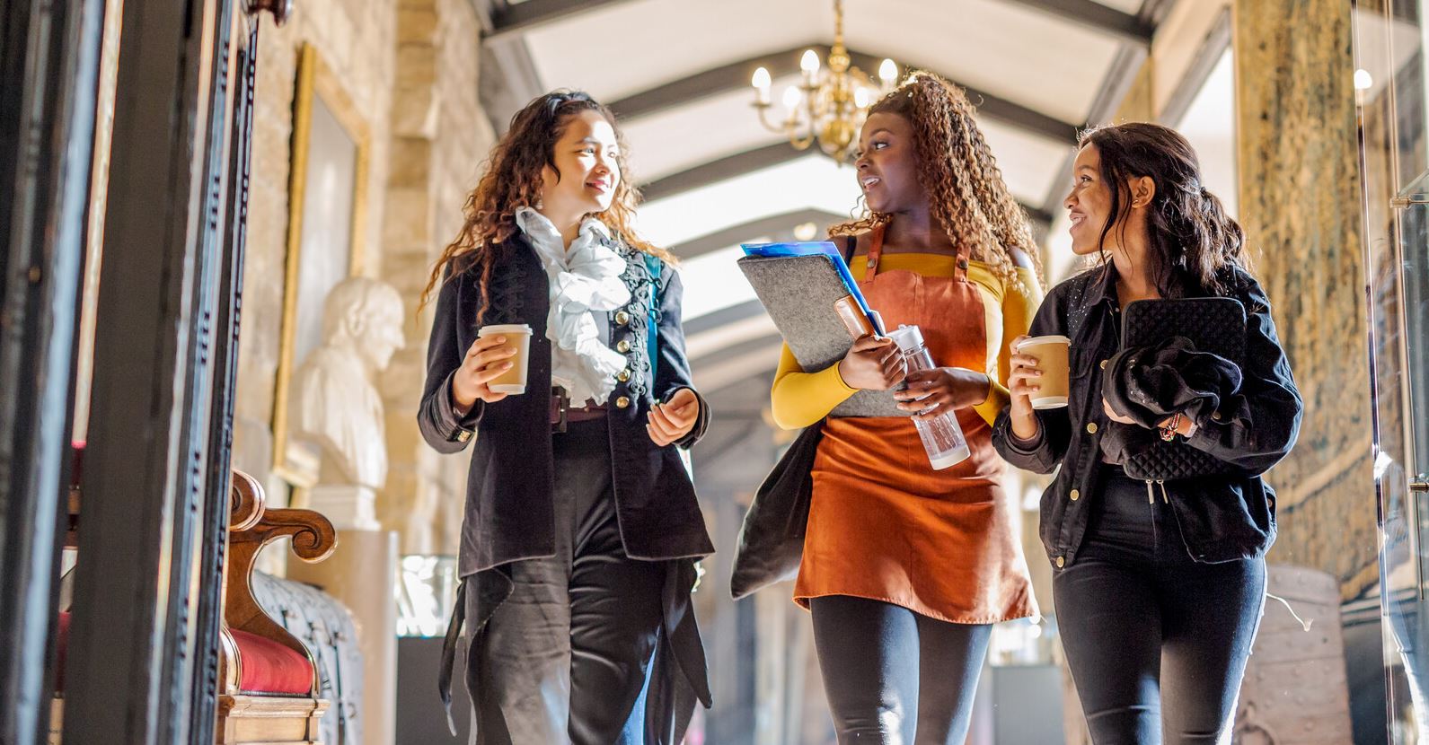 Three female students walking down a corridor chatting