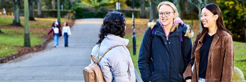 Three females in conversation outside the University