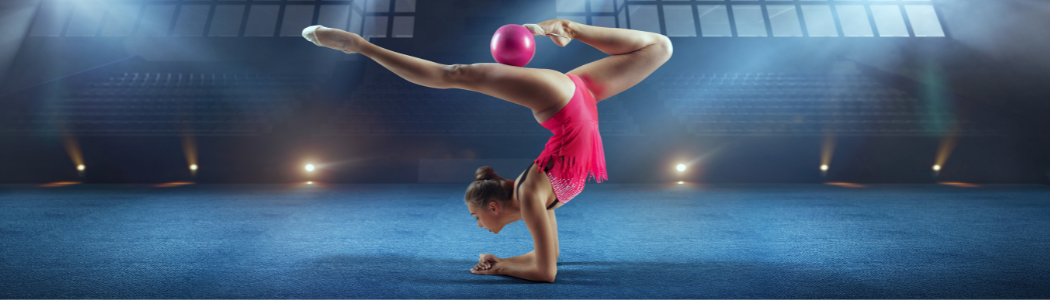 A female gymnast performing a gymnastic manoeuvre with a ball.