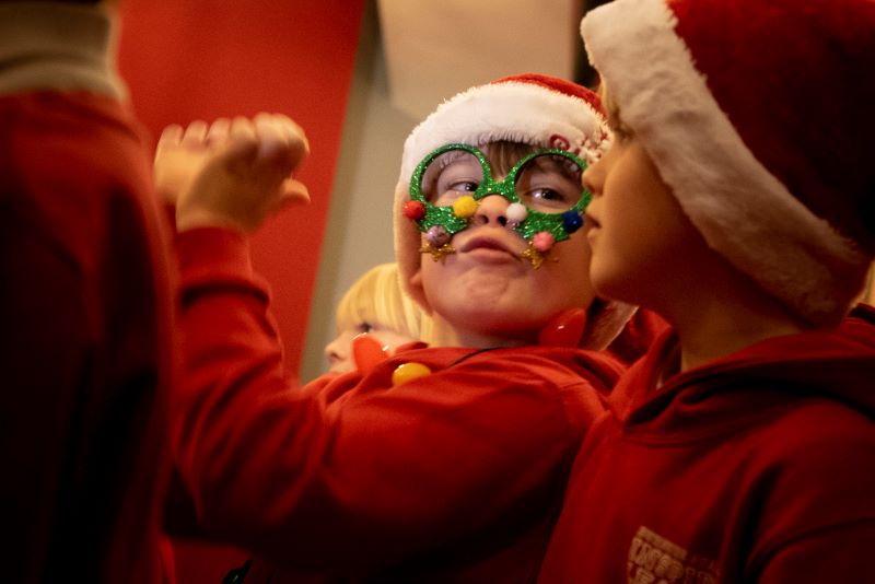 A young boy wearing christmas glasses is happy to be singing at Collingwood