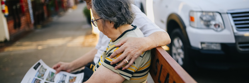 Elderly couple on bench reading newspaper