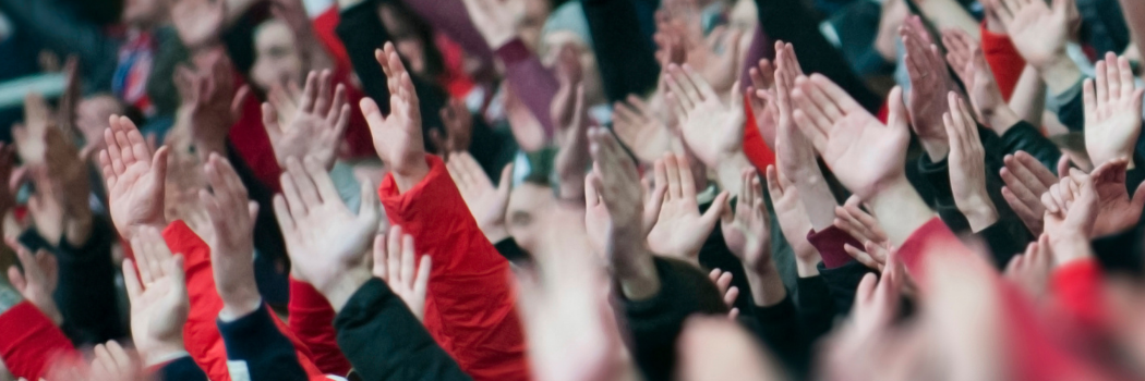 Fans with their hands in the air cheering in a sports stadium