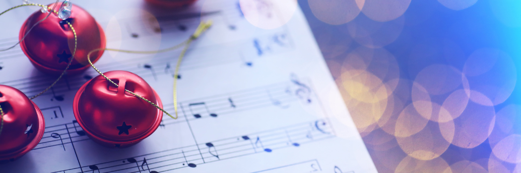 Sheet music with red jingle bells laid on top