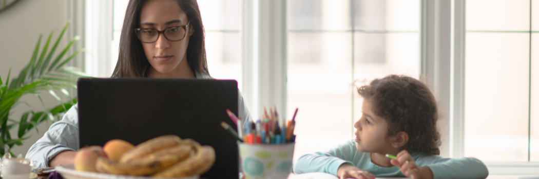 Woman on laptop with child writing