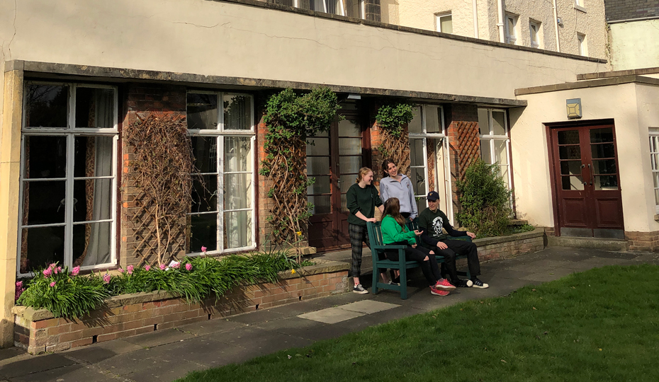 Students sitting on a bench in the back garden of Cuth's buildings on the Bailey.