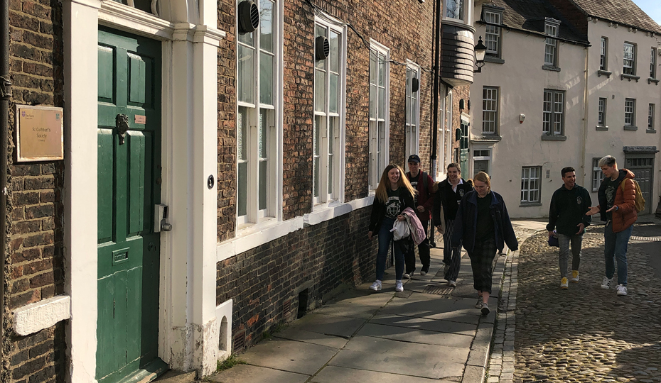 View from North to South Bailey with students walking down the cobbled street past historical buildings.