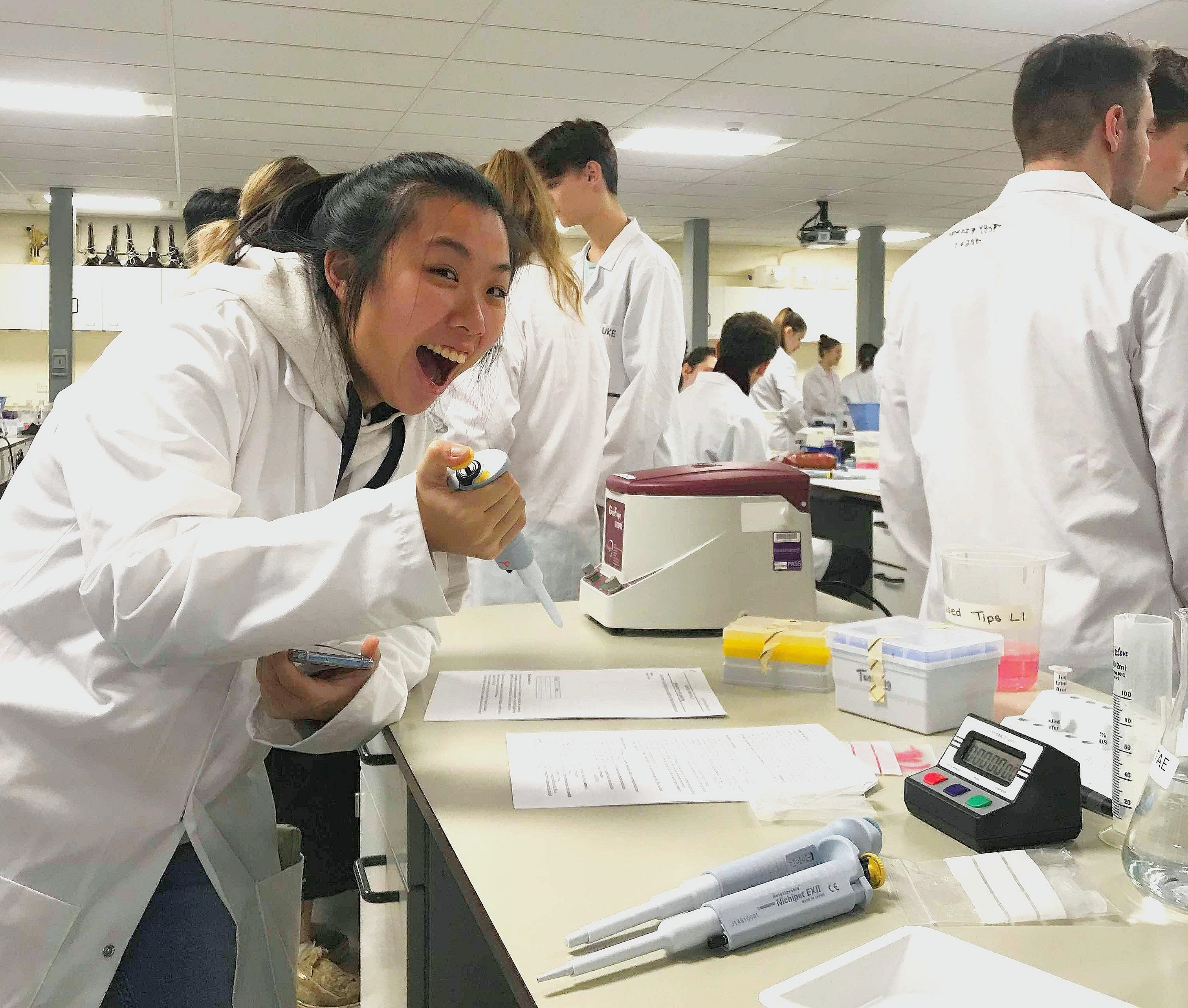 Durham Inspired Award Student in a lab smiling whilst using the scientific equipment