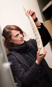 Female student holds up a scrimshaw tusk or bone