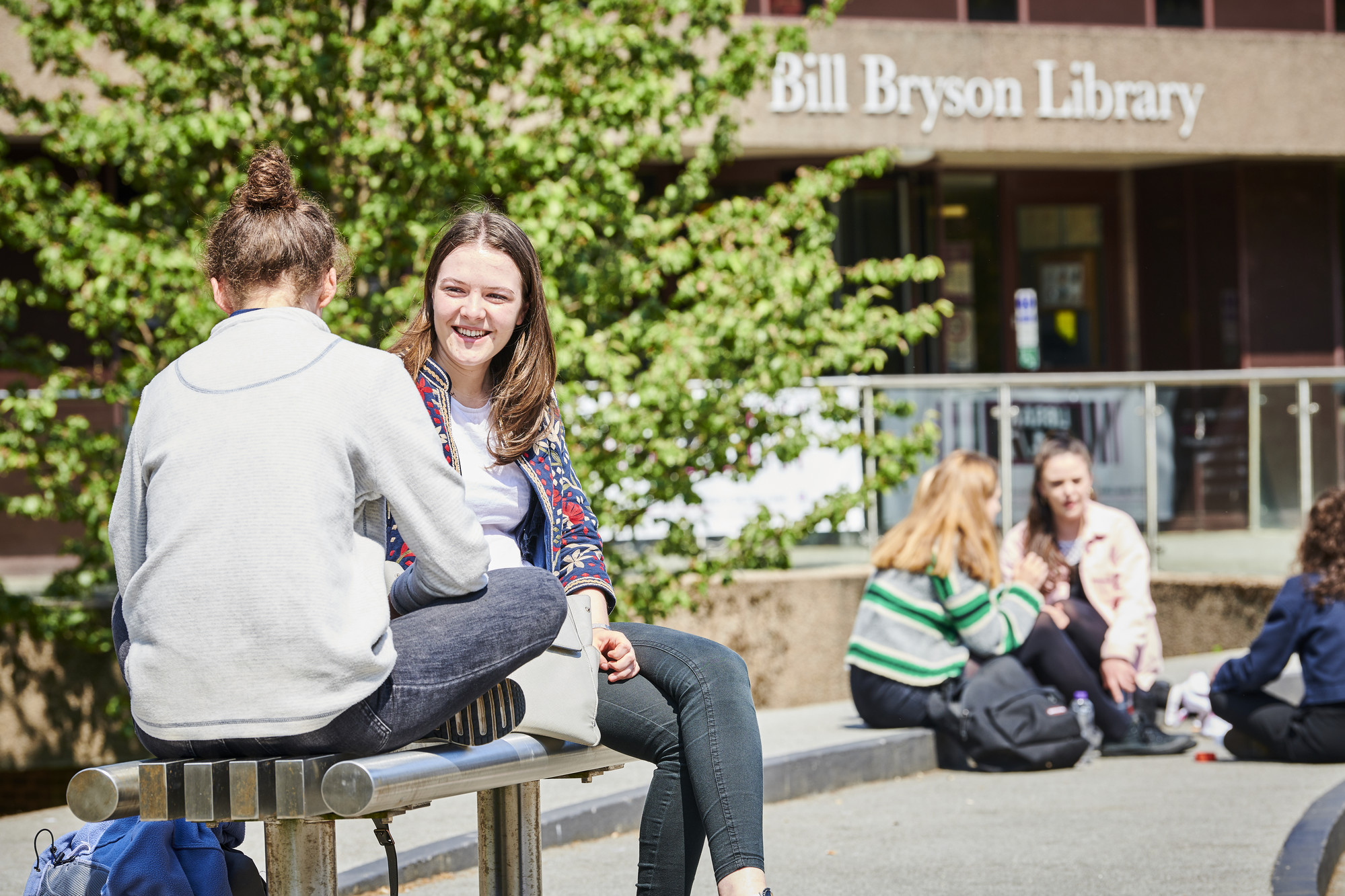 2 students sitting on a bench chatting