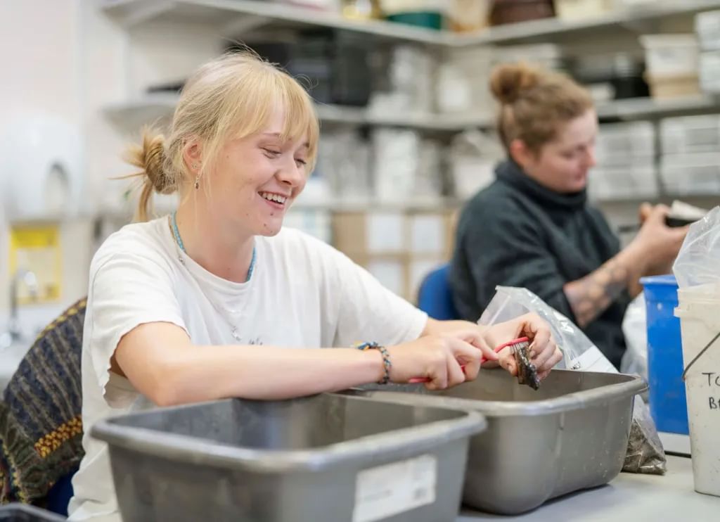 Archaeology placement year students in a lab space cleaning and examining artefacts