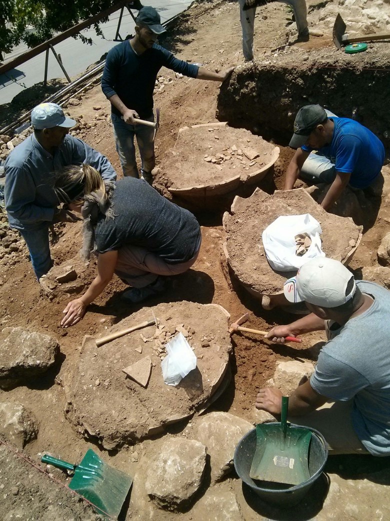 A group of archaeologists excavating ceramic vats