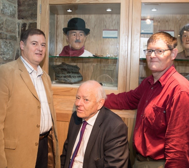 Three generations of the Lister family next to a facial reconstruction of their ancestor