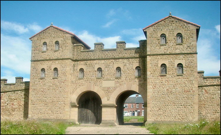 Photograph of a stone  reconstructed Roman Fort Gateway with two archway entrances with flanking towers