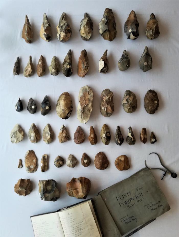 An assemblage of handaxes displayed alongside a ledger titled Flints from Fordwich High Pit Herne Bay museum