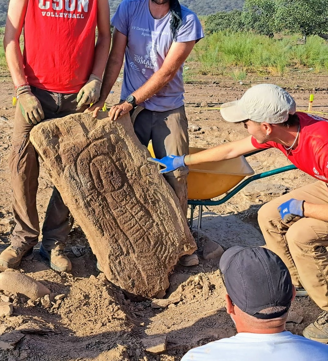 Four archaeologists around a newly excavated stela, discovered in its original context.