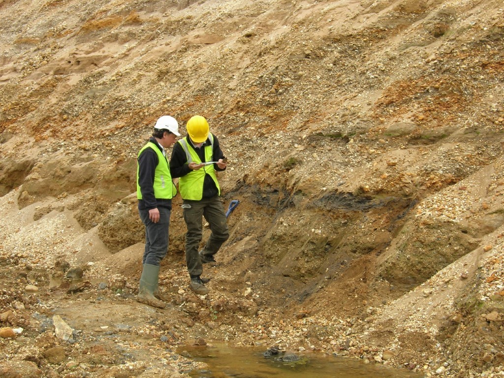 Two academics in high viz jackets and hard hats in a quarry