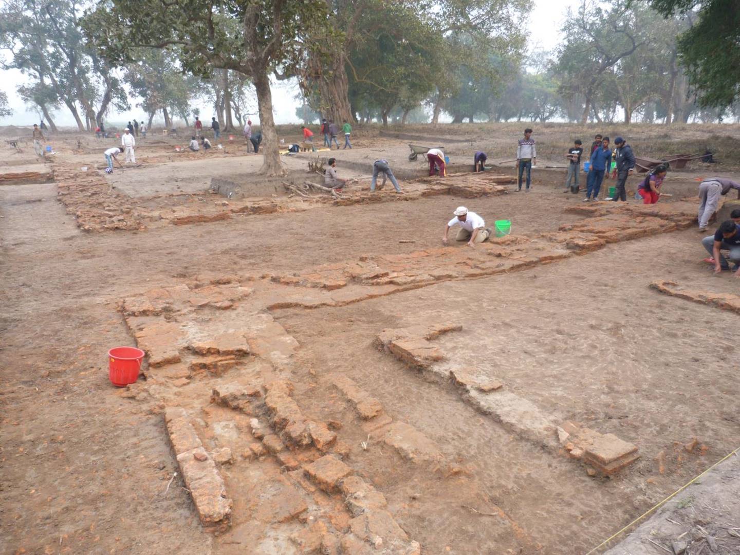 Photograph of archaeological excavations of stone building foundations underway