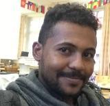  An early career researcher, Mohamed Bashir, wearing a grey top, smiling at the camera.