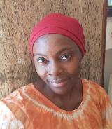 An early career researcher, Ruth Wafang, smiling at the camera wearing a white and orange shirt and red headwrap.