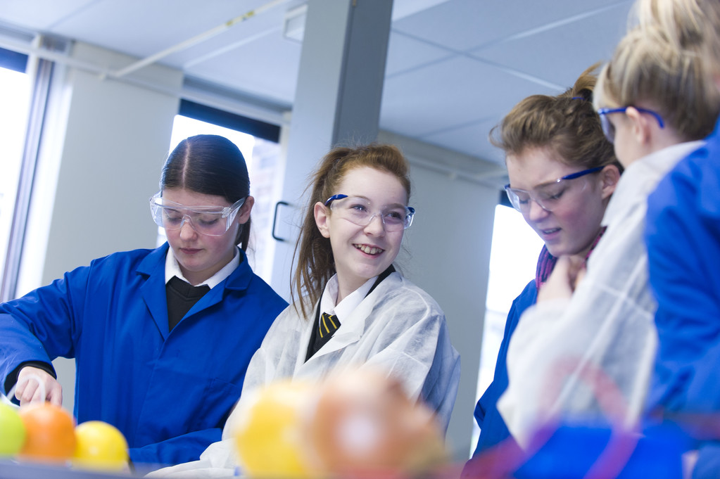 TYoung students smiling and wearing protective eye equipment