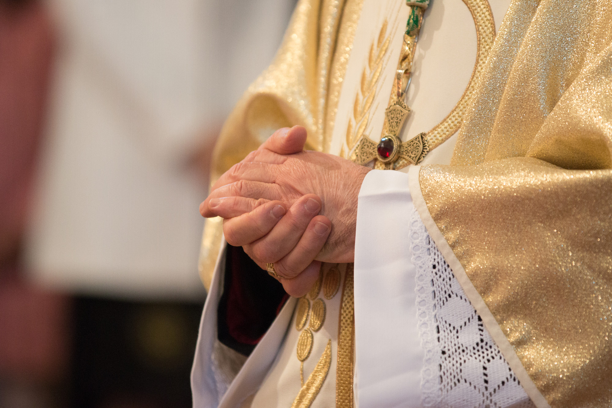 TCatholic priest holding praying hands