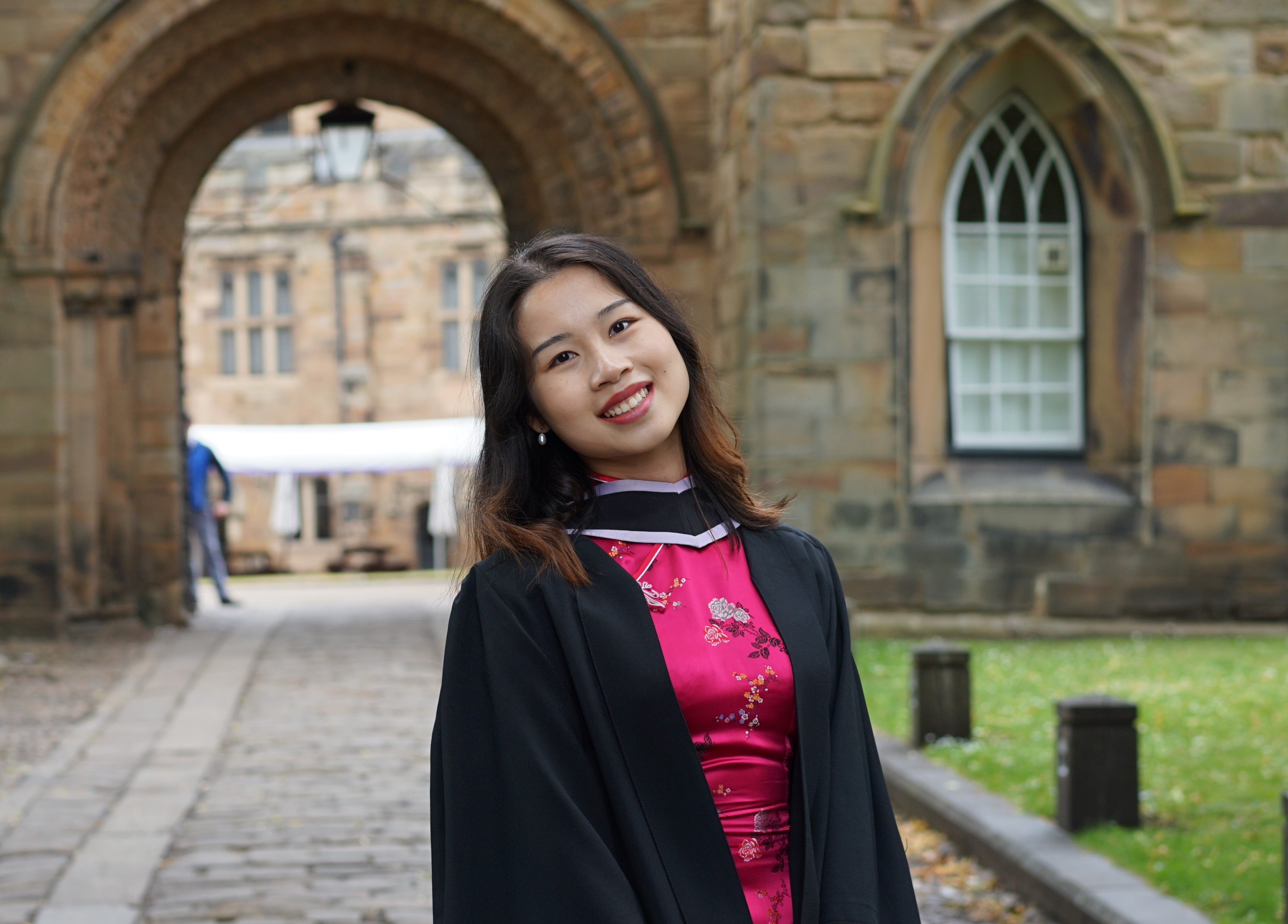 a female student wearing a black robe and bright pink top