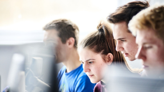 TThree students sitting at computers.