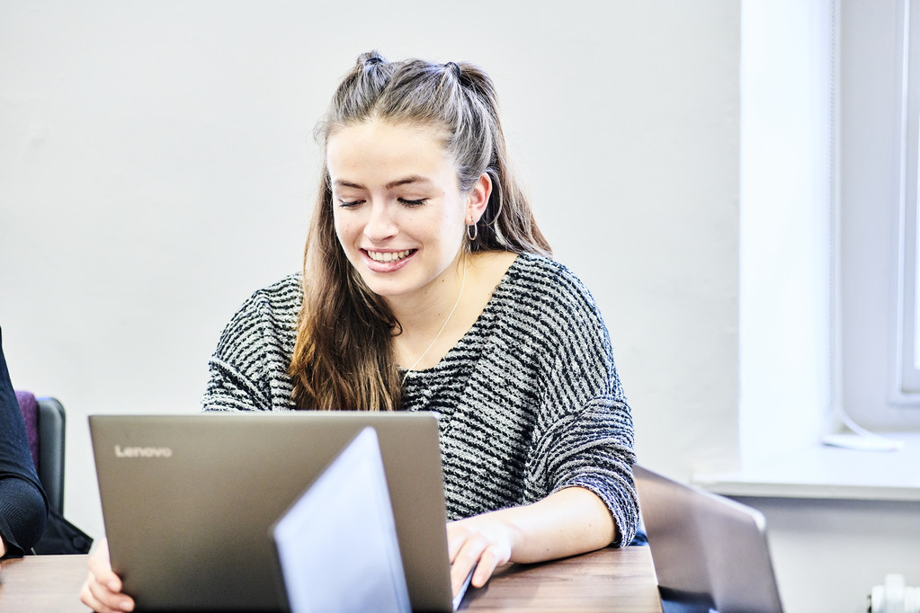 Female student smiling while typing on laptop in seminar