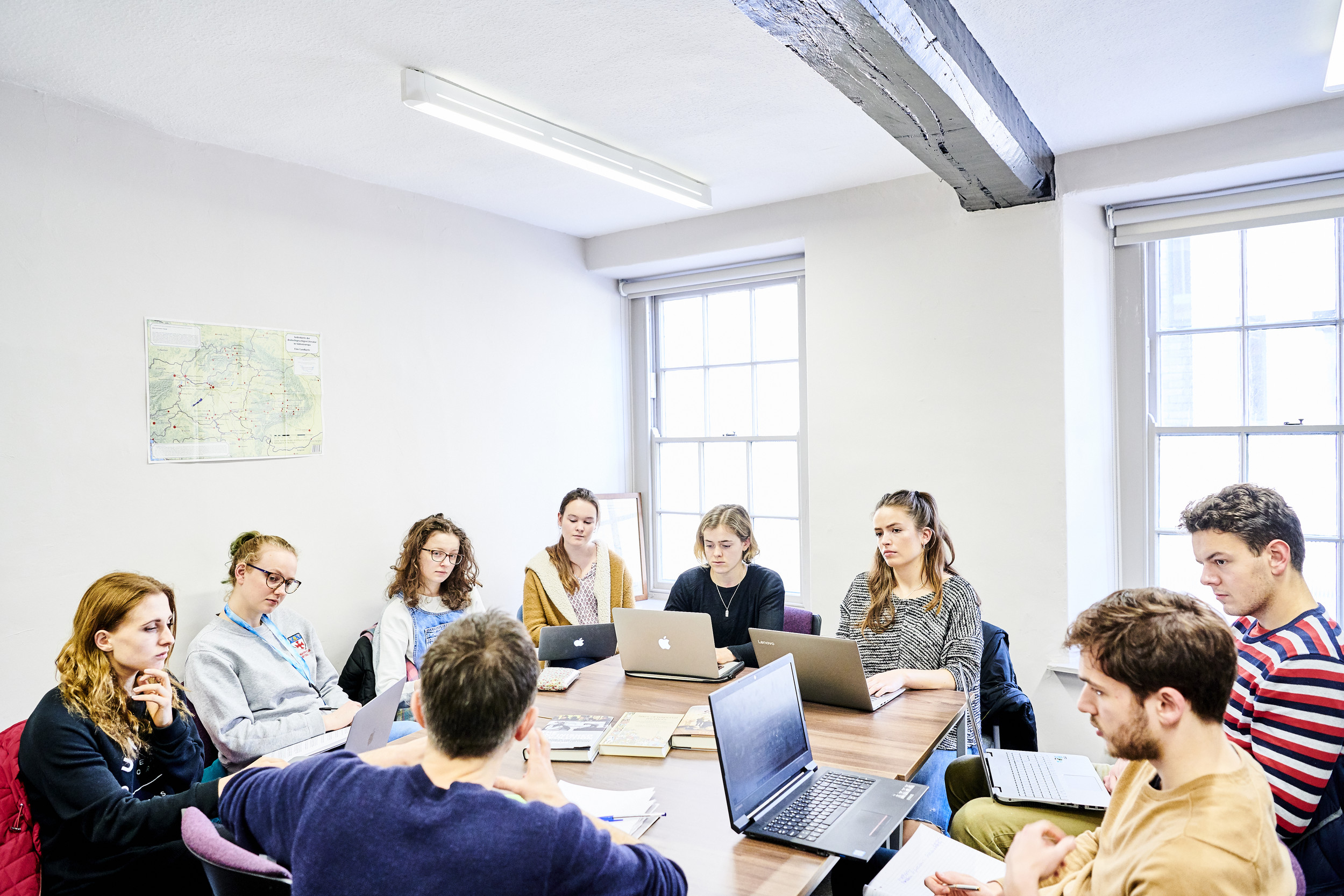 Students sitting round a table with laptops in a seminar