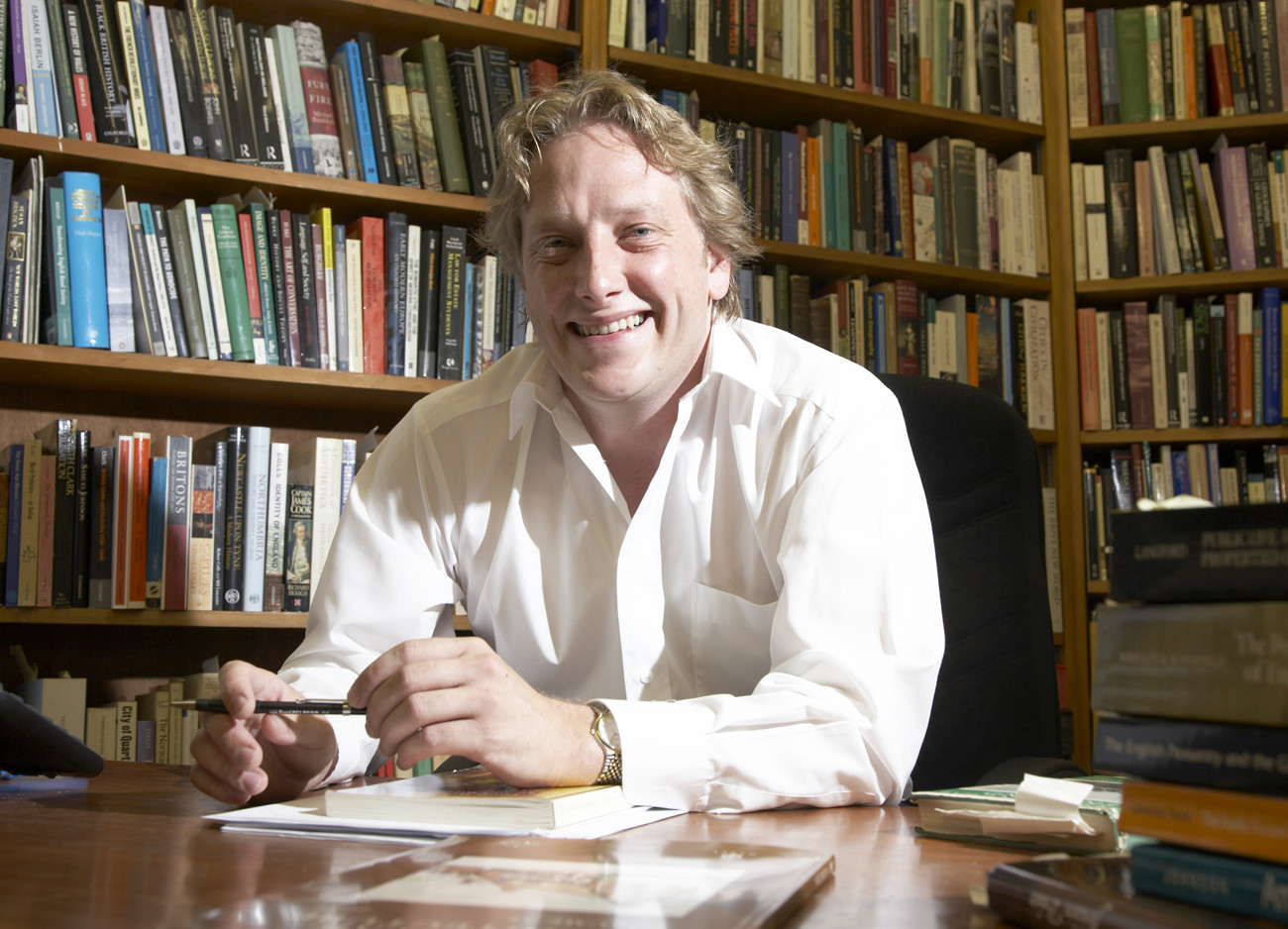 Headshot of Dr Adrian Green in front of a bookshelf