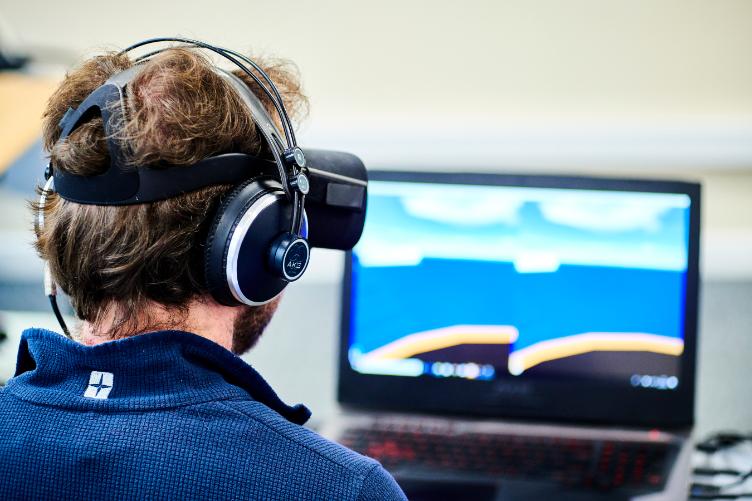 Researcher wearing VR headset sat with laptop trialling an experiment